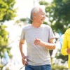 elderly couple jog through park smiling at each other
